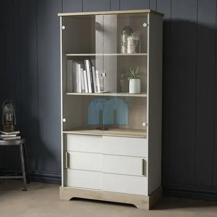 Moderne vitrinekast met houtafwerking en witte laden, voorzien van glazen deuren en metalen handgrepen, ideaal voor het stijlvol tentoonstellen van boeken en decoratieve objecten in een hedendaags interieur.